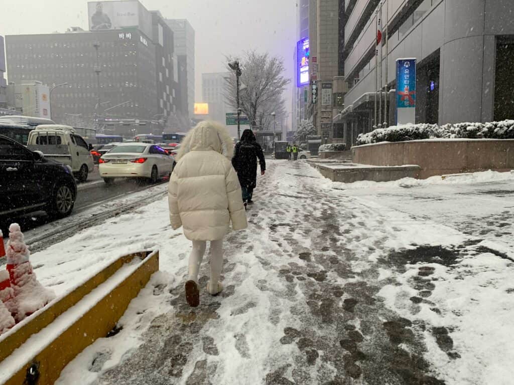 Woman wearing a white parka and slippers during winter in Seoul, South Korea